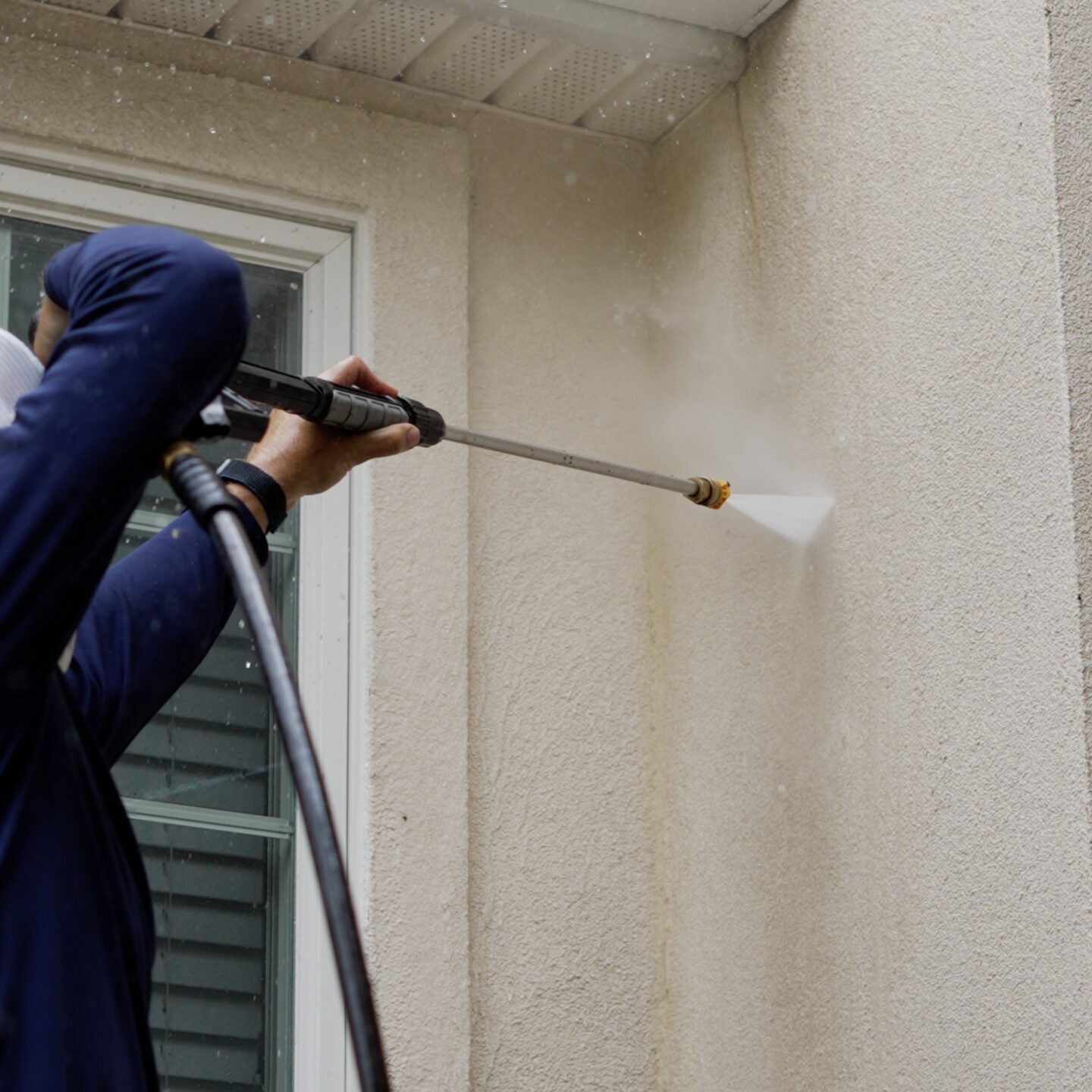 man pressure washing house